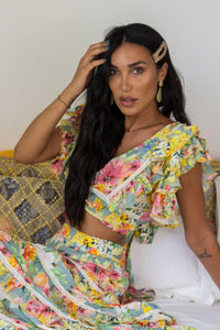 TROPICAL VINTAGE FLORAL PRINTED FLUTTER SLEEVE CROP TOP WITH DELICATE CROCHET TRIM ACROSS THE BODICE AND TIE BACK BOW DETAIL AT THE BACK.