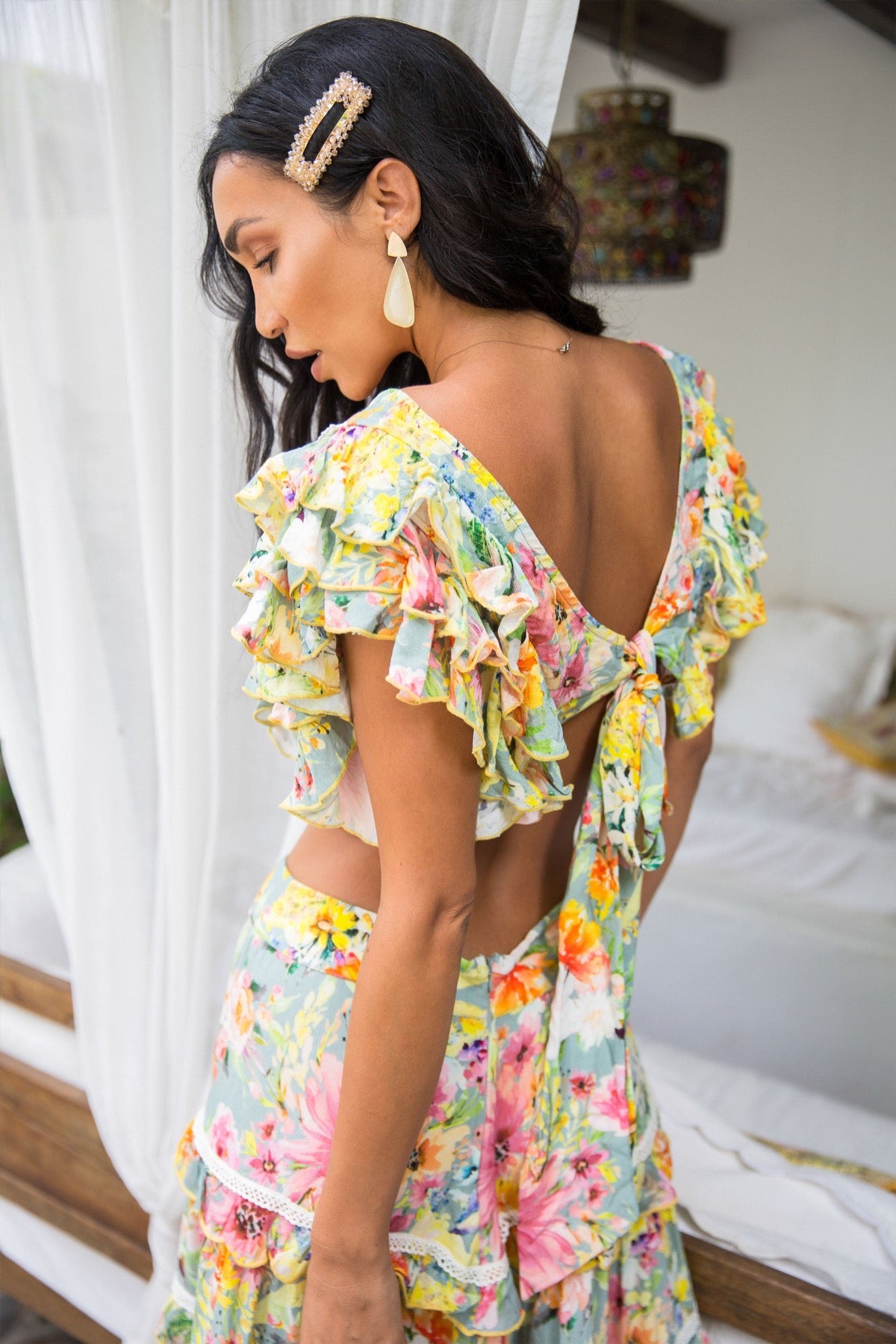 TROPICAL VINTAGE FLORAL PRINTED FLUTTER SLEEVE CROP TOP WITH DELICATE CROCHET TRIM ACROSS THE BODICE AND TIE BACK BOW DETAIL AT THE BACK.